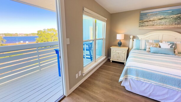 A bedroom with a large window, a bed with striped bedding, a nightstand, and a painting on the wall. - L👀K! NEW LISTING! Lakefront; Boat Ramp. Lake Powell! Rent both sides - sleeps 18 (Panama City Beach)