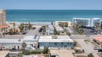 A coastal cityscape with a beach, parking lots, and buildings.