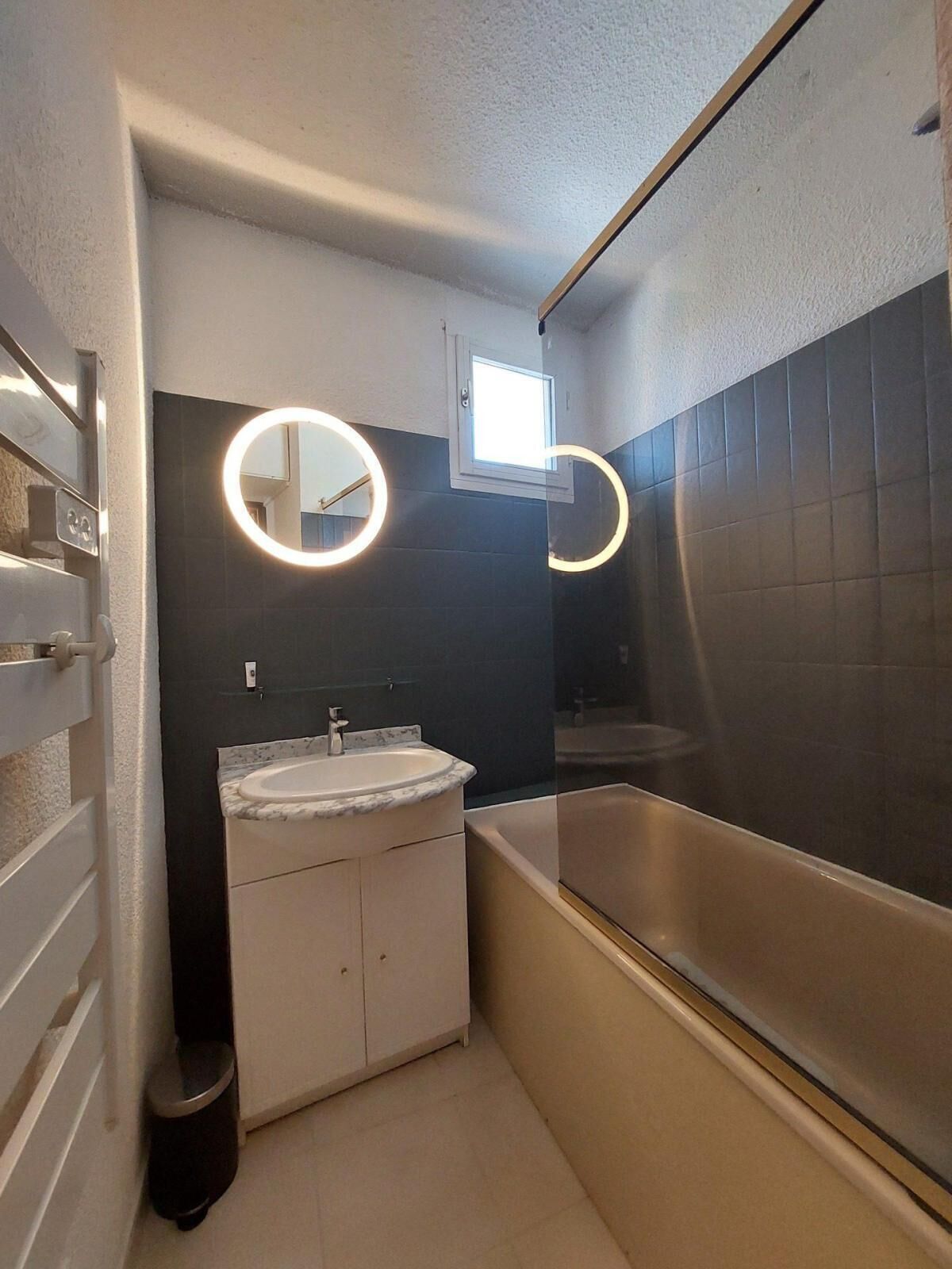 A compact bathroom with a white sink, a mirror, and a bathtub.