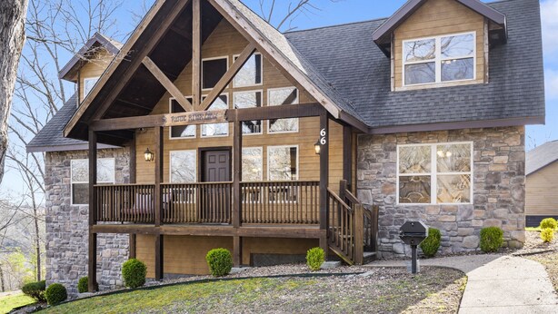 A two-story stone building with a wooden deck and a stone chimney. - Lodge Near SDC with 4 King Suites and Pools (Branson)