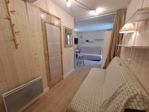 A room with a bed, a radiator, a wooden coat rack, a mirror, and a door labeled 'TOILET'.