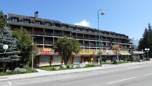 A multi-story hotel with balconies, a visible restaurant, and a clear sky.