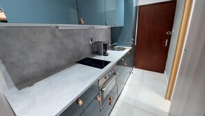 A modern kitchen with grey countertops, a black induction cooktop, and stainless steel appliances.