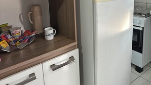 Una cocina compacta con un refrigerador blanco, una cafetera y una licuadora sobre la encimera.