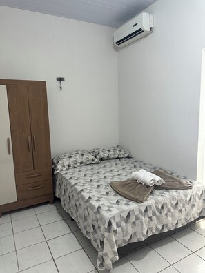 Un dormitorio con cama, armario y aire acondicionado.