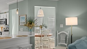 A modern kitchen with white cabinetry, a dining area with white chairs, and a light blue sofa.