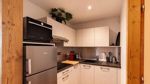 A compact kitchen with stainless steel appliances, a wooden countertop, and light-colored cabinetry. - 50m from ski slopes, 2nd floor, fitness, swimming pool, sauna, balcony, fireplace or stove, tv (Les Orres)