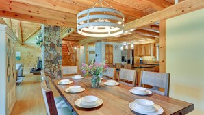 A wooden dining table set with plates and a vase of flowers, surrounded by chairs. - Pocono Dog-Friendly Home on River (Damascus)