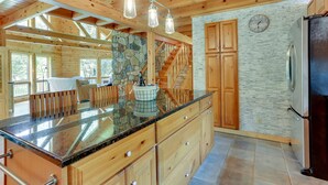 A spacious kitchen with wooden cabinets, a granite countertop, and a stone accent wall. - Pocono Dog-Friendly Home on River (Damascus)