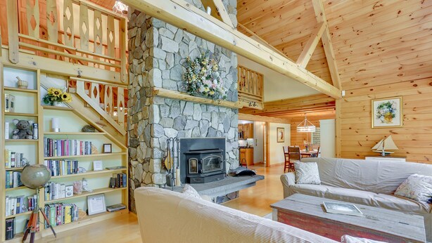 A cozy living room with a stone fireplace, wooden bookshelves, and a comfortable seating area. - Pocono Dog-Friendly Home on River (Damascus)