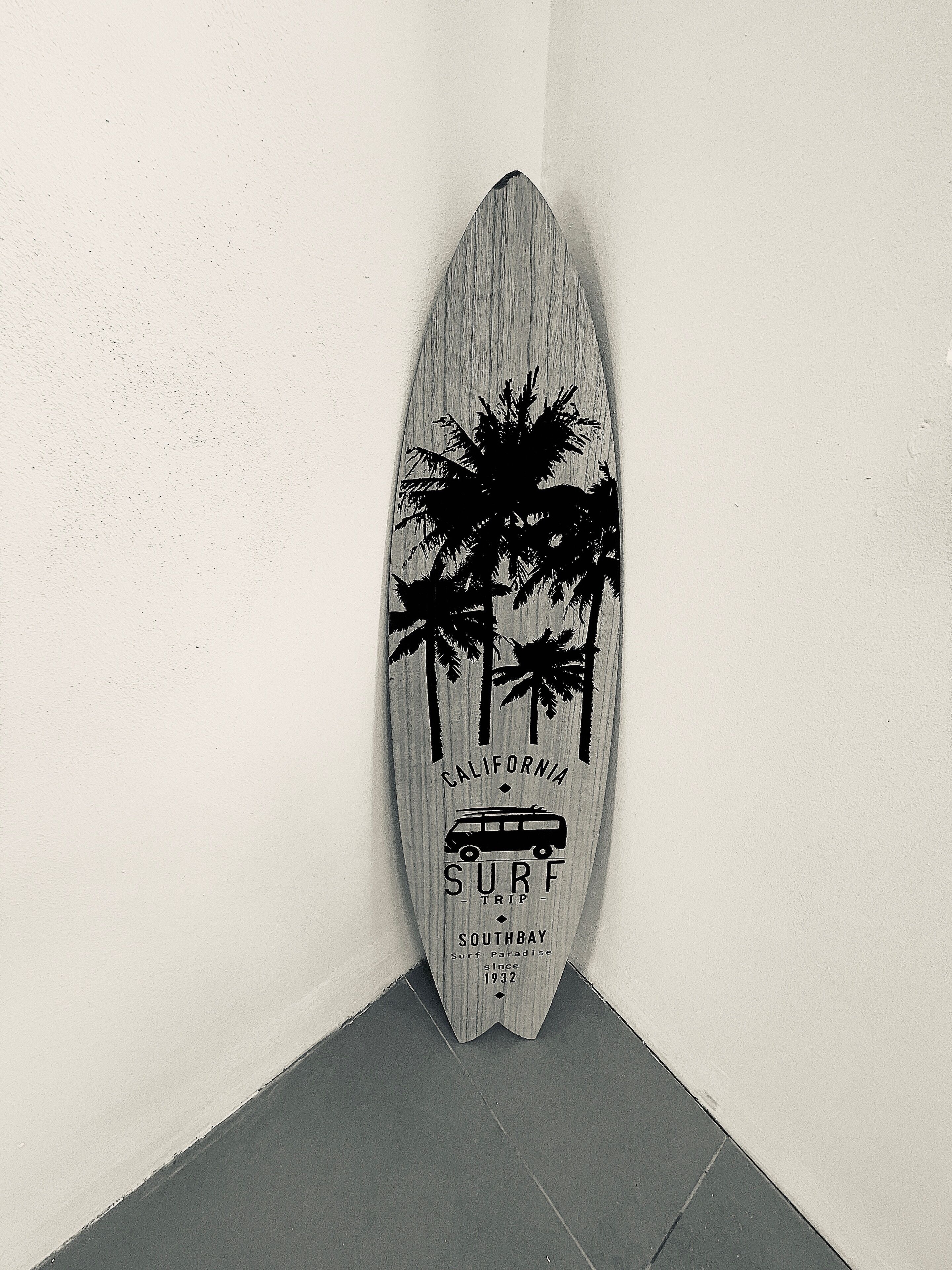 Una tabla de surf con un diseño de palmeras y el texto 'California Surf Trip Southbay since 1932'.