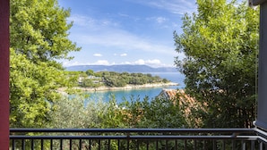 Un balcon donnant sur un lac, entouré d’arbres et avec des montagnes visibles au loin.