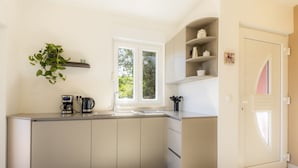 Une cuisine moderne dotée d’un îlot central intégré, d’une fenêtre et d’une porte ornée d’un panneau de verre décoratif.
