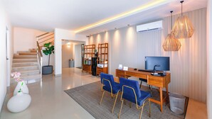 Ein modernes Wohnzimmer mit Treppe, Schreibtisch und Computer sowie einem Fernseher.