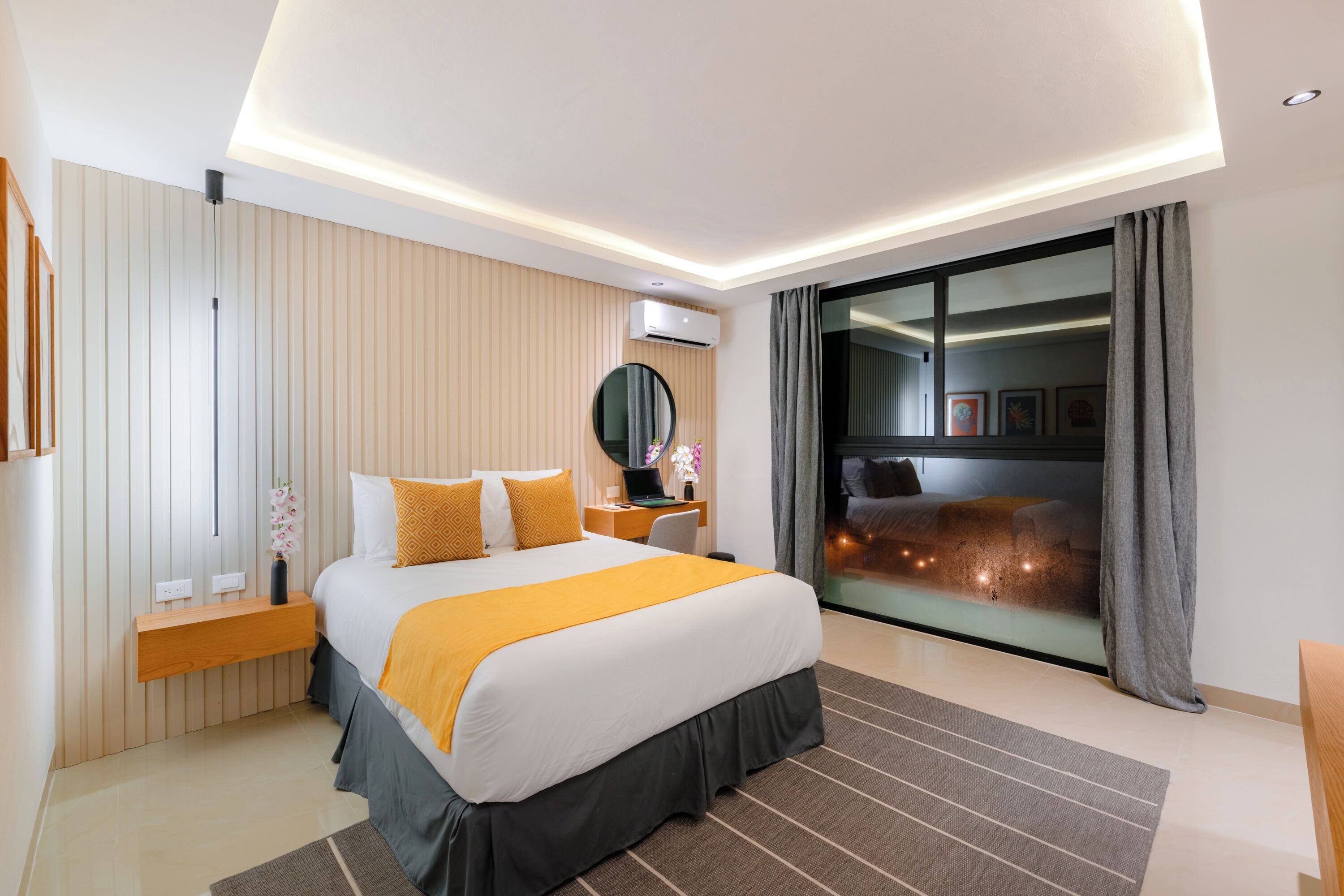 Une chambre d’hôtel moderne avec un grand lit, un bureau et une vue sur la ville la nuit.
