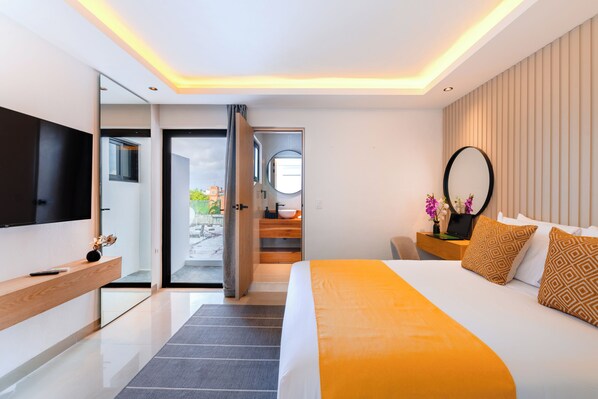 Una habitación de hotel moderna con una cama grande, un televisor de pantalla plana, una mesita de noche de madera y vistas a través de una puerta abierta.