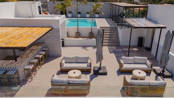 A rooftop terrace with a swimming pool, sun loungers, and a dining area.