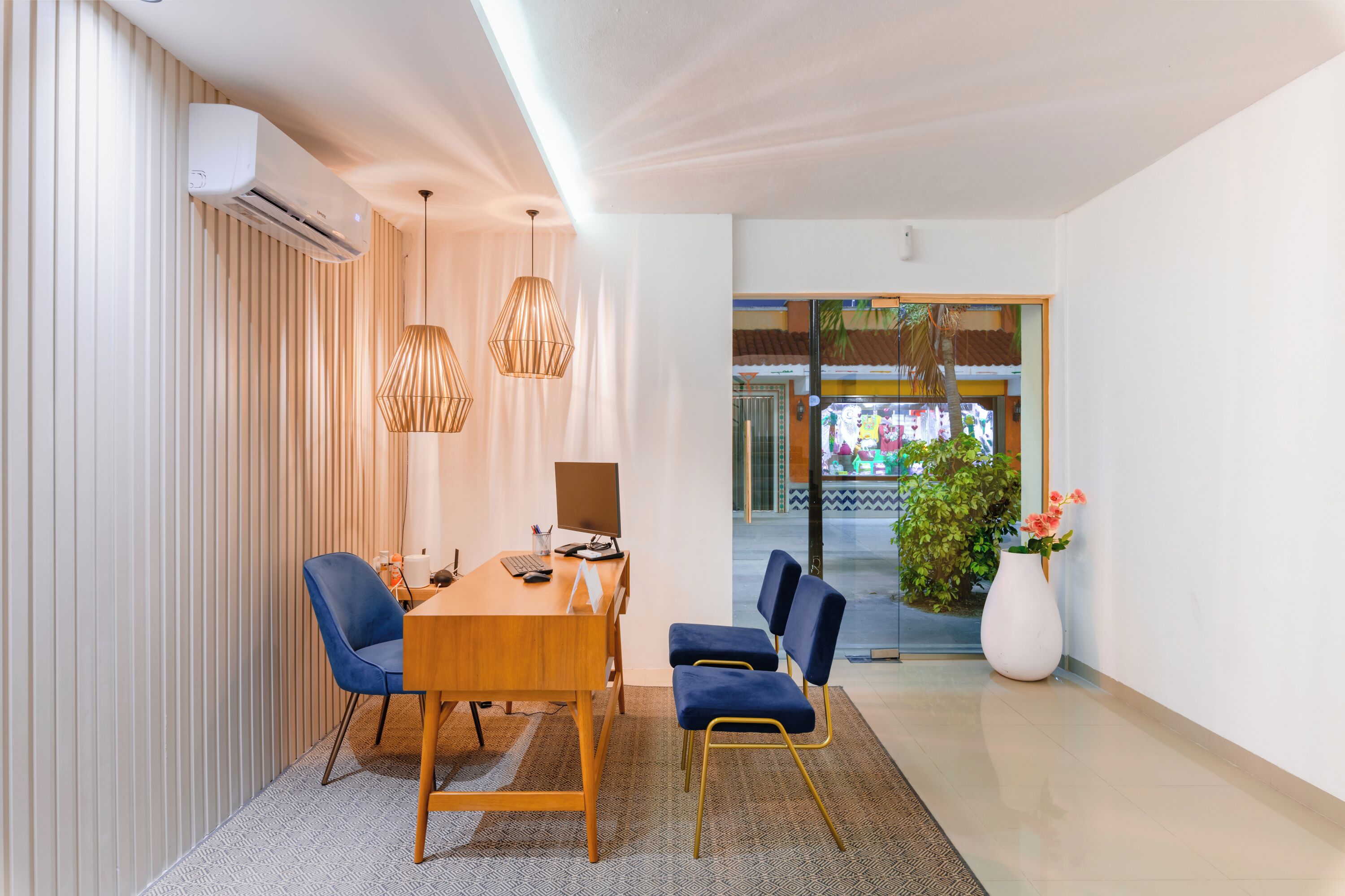 Un comedor moderno con mesa de madera, sillas azules y lámparas colgantes.