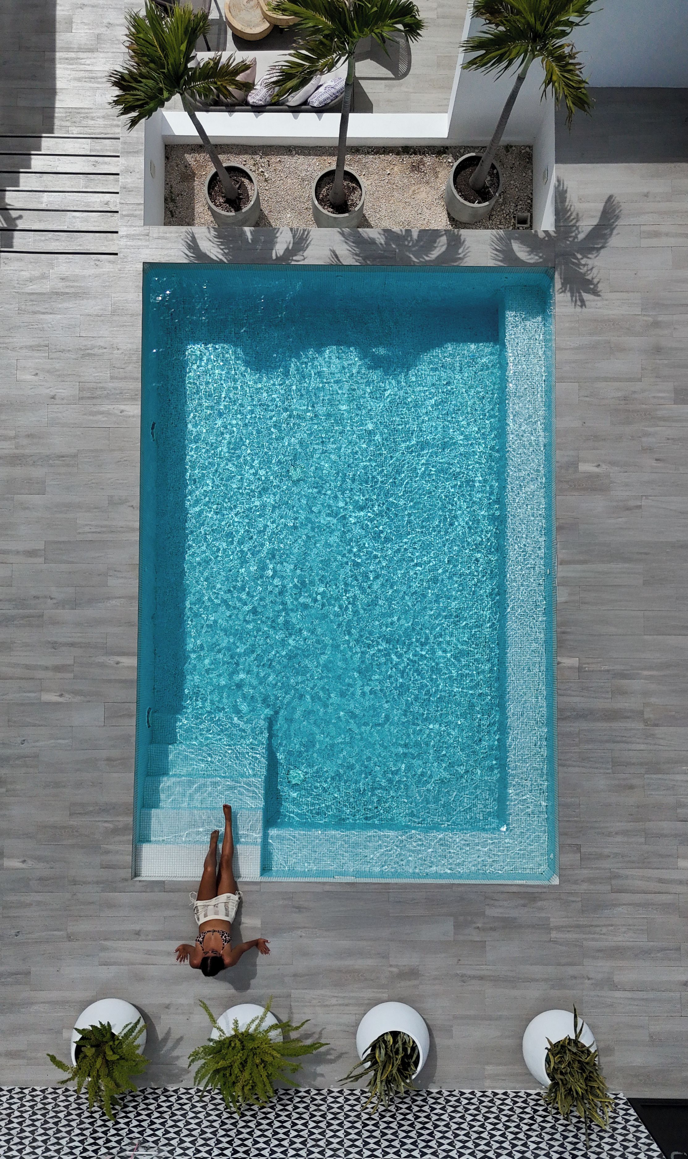 Une piscine rectangulaire entourée d’une terrasse carrelée.