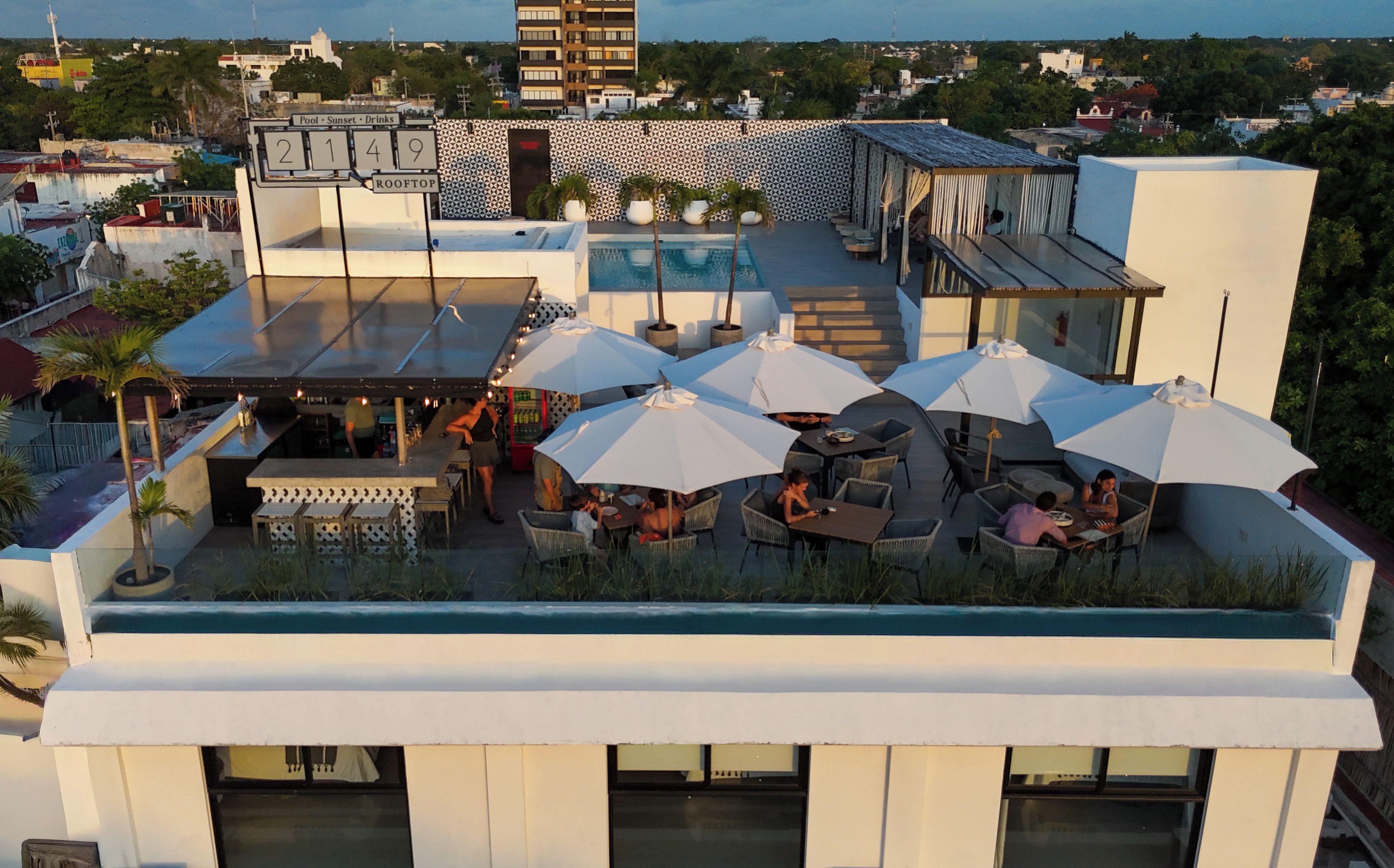 Un bar situé sur un toit, avec des places assises en plein air et des parasols, offrant une vue sur le paysage urbain.