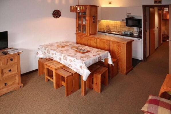 A compact kitchen with a wooden table and bench, a small cabinet, and a microwave.