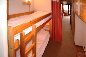 A bunk bed room with a wooden headboard, a wall-mounted light, and a red curtain. - 40m from ski slopes, floor -1, balcony, 30m², Les Orres (Les Orres)