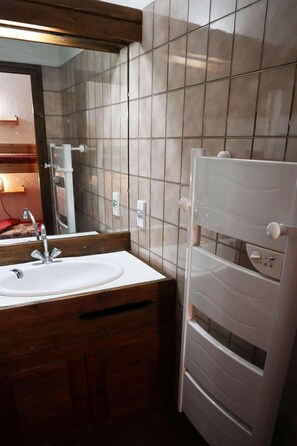 A bathroom with a sink, mirror, and a white towel rack.