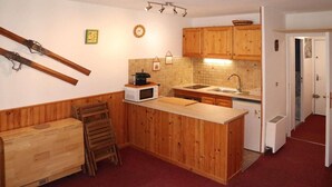 Eine kleine Küche mit Holzausstattung, einer Mikrowelle und einem Spülbecken.