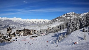 Ein Skigebiet mit mehreren Gebäuden, Skipisten und schneebedeckten Bäumen.