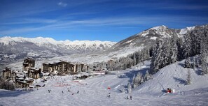 A ski resort with multiple buildings, ski slopes, and snow-covered trees.