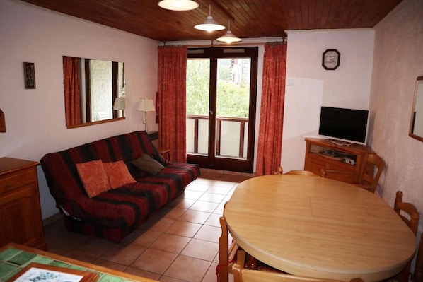 A cozy living room with a sofa, a dining table, and a television.