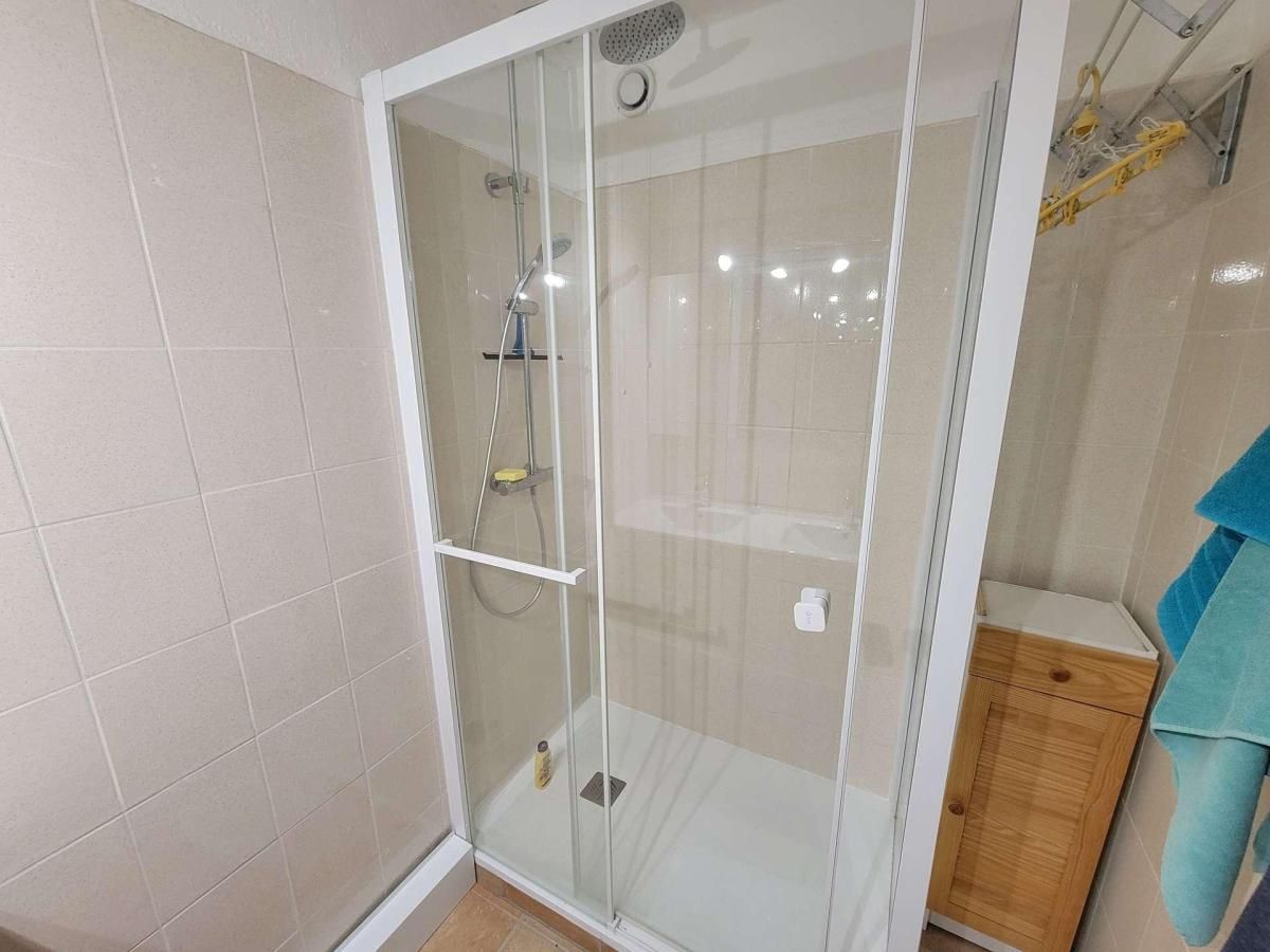 A glass-enclosed shower with a handheld showerhead and a wall-mounted faucet.
