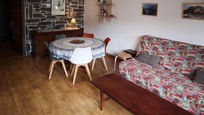 Een gezellige woonkamer met een ronde tafel, een gestreept sofa en een stenen muur.