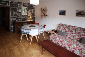 A cozy living room with a round table, a patterned sofa, and a stone wall.