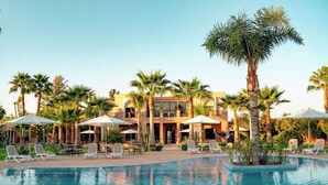 A hotel with a swimming pool, palm trees, and outdoor seating areas. - Charming 14-bed Villa in Marrakech (Tameslouht)