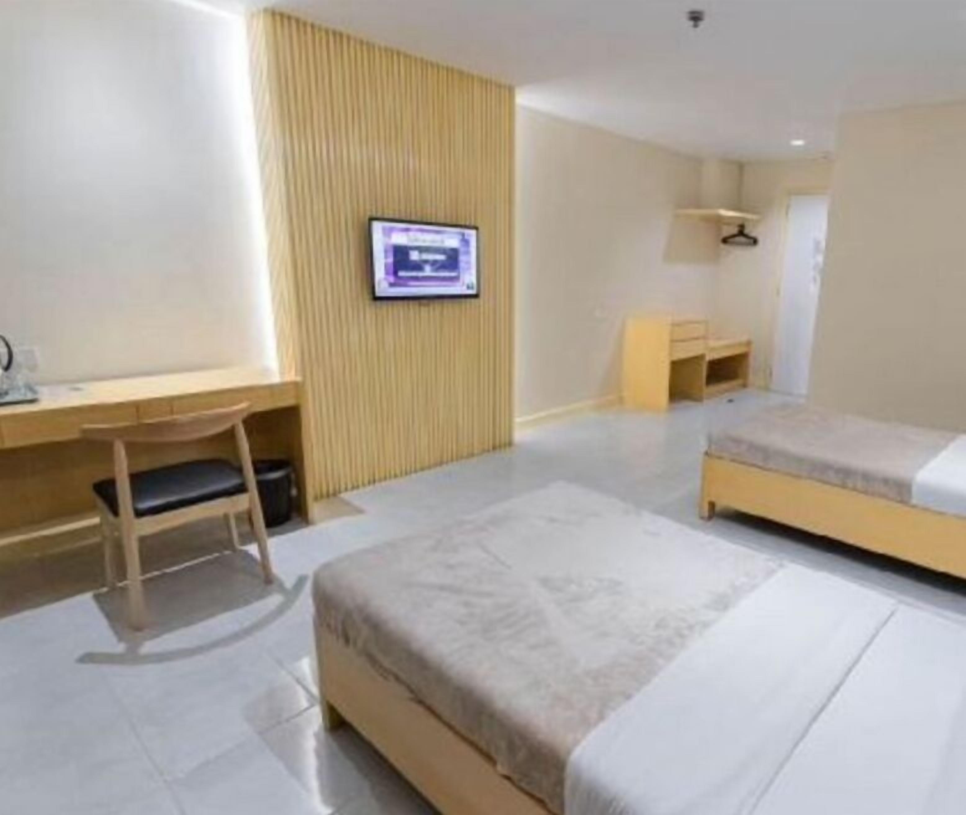 A hotel room with a bed, a desk, a chair, a television, and a wardrobe.