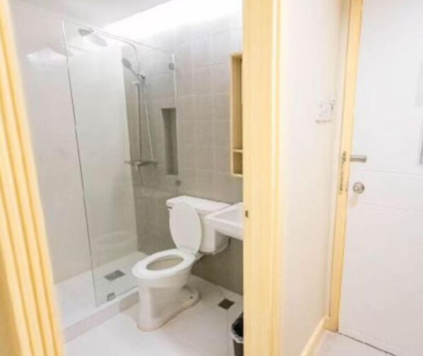 A bathroom with a glass-enclosed shower, a toilet, and a sink.