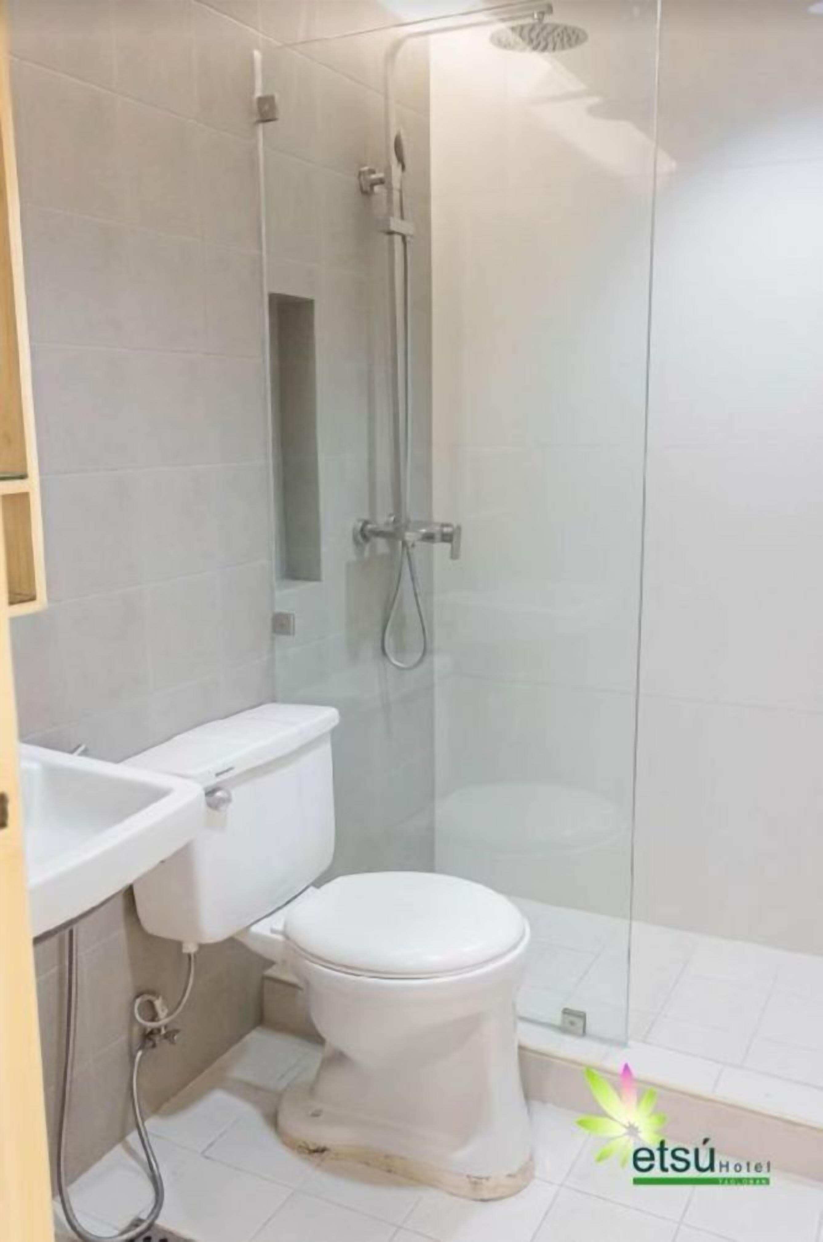 Une salle de bain comprenant des toilettes, un lavabo et une douche séparée par une paroi en verre.