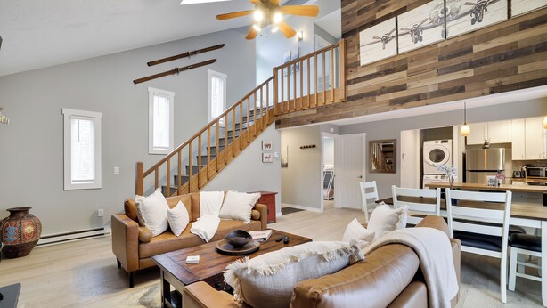 A spacious living area with a high ceiling, a wooden staircase, a dining area, and a kitchen. - Cabin in the heart of Poconos! A Pocono Bliss! Close to Kalahari and Camelback (Tobyhanna)