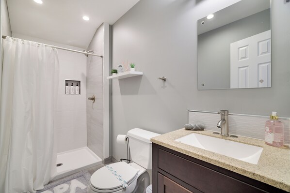 Un baño moderno con ducha, inodoro, lavamanos y espejo.