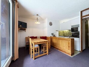 A compact living space with a dining table, wooden cabinets, a kitchenette, and a television. - 10m from ski slopes, 7th floor, balcony, 22m², Les Orres (Les Orres)