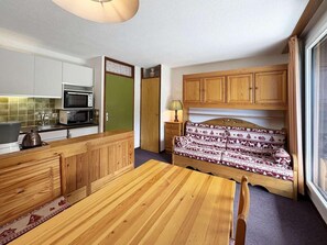 A compact room with a kitchenette, a bed with patterned bedding, and a window. - 10m from ski slopes, 7th floor, balcony, 22m², Les Orres (Les Orres)