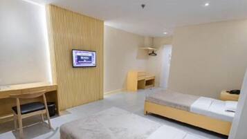 A modern hotel room with a desk, a bed, a TV, and a wardrobe.