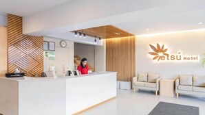 A hotel reception area with a modern design, featuring a reception desk, a receptionist, and a logo on the wall. - Chic Comforts: Etsu Hotel's Signature Studio Await (Tacloban)