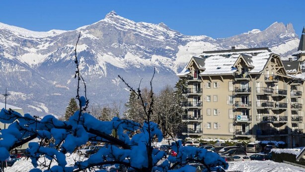 Un hôtel à plusieurs étages, doté de balcons, qui se dresse sur fond de montagnes enneigées.