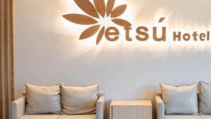 Un espace d’accueil d’hôtel avec un logo et deux canapés dotés de coussins.