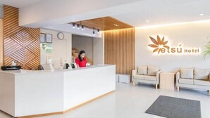 Un espace d’accueil d’hôtel au design moderne, avec un réceptionniste et un logo affiché sur le mur.