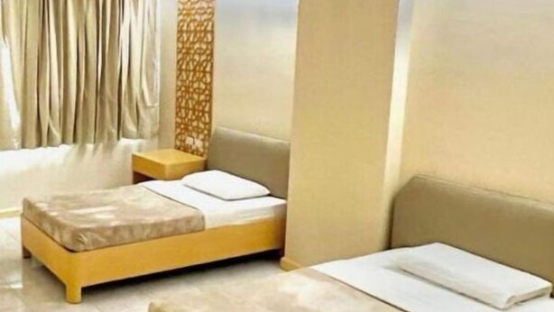 Une chambre d’hôtel avec deux lits simples, une petite table et un panneau décoratif mural.