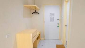 A narrow hallway with a wooden bench, a door at the end, and a small mat on the floor.