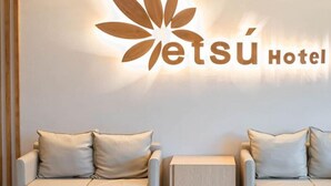 Ein Hotel-Empfangsbereich mit Logo, zwei Sofas und einem kleinen Holztisch.